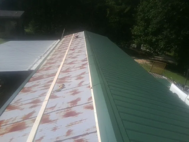 Old rusted panels beside newly installed green metal roofing — Wind Damage Roof Repair by Roofing Brothers in Hunt Valley