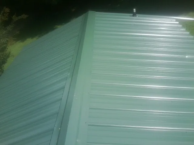 New green metal panels meeting at the ridge of a roof — Flat Roof Repair work by our crew in Hunt Valley