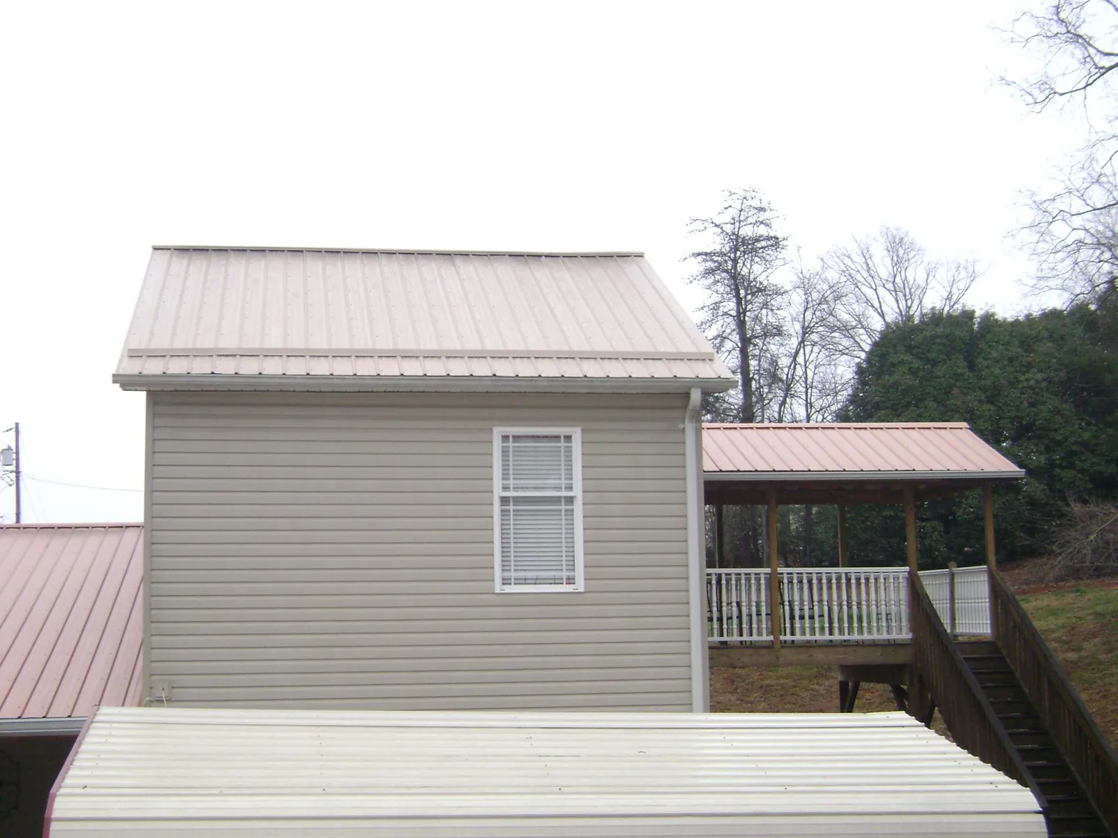 Tan metal roofs on a two story addition and attached porch, from a Roof Replacement job in Hunt Valley