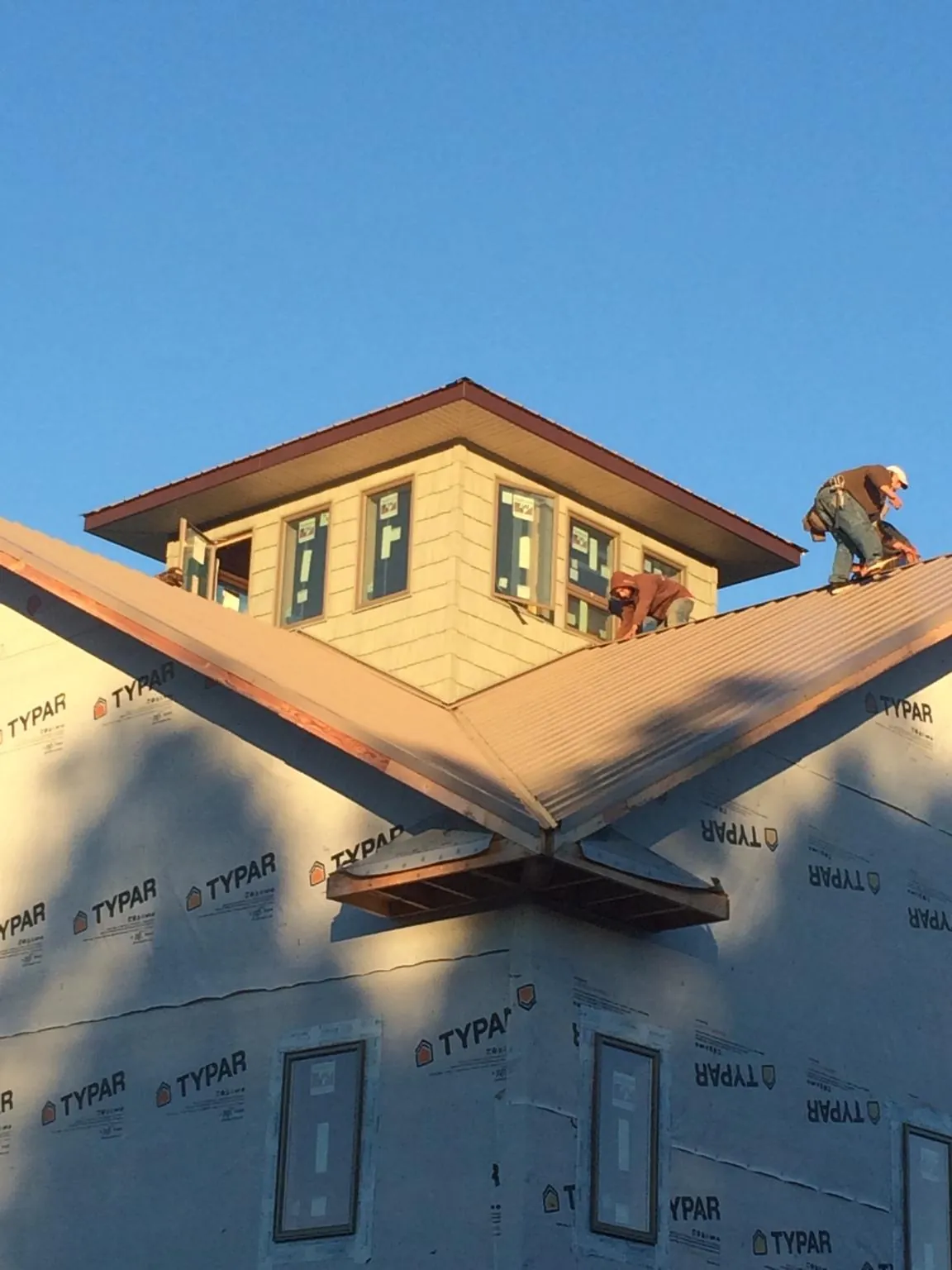 Roofers working around a rooftop cupola on a new metal roof at sunset — Roof Waterproofing in Hunt Valley by Roofing Brothers